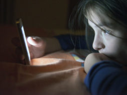 Teenager sending email from smart phone in her bed