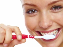 Pretty young woman brushing her teeth isolated