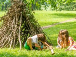 outdoor portrait of three happy kids – boy and girls – playing n