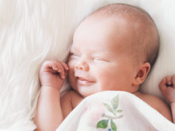 Sleeping newborn baby in a wrap on white blanket.