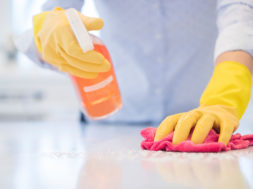 Close Up Of Woman Using Spray Polish To Clean Kitchen Surface