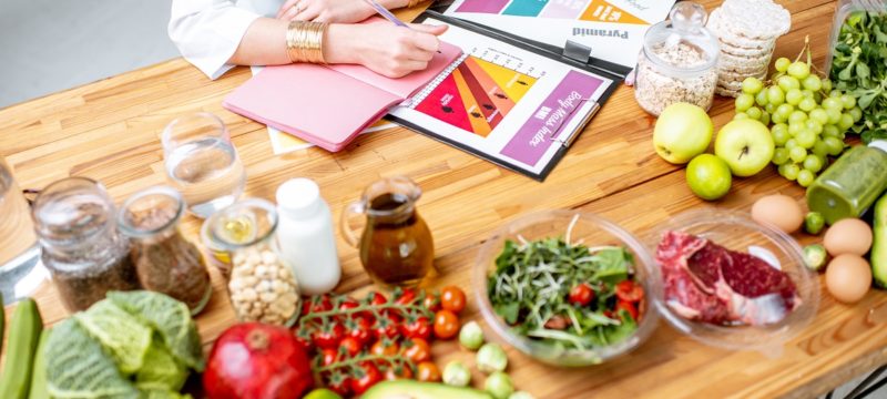 Writing a diet plan on the table full of healthy food