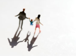 Figurines of family with child on white background, casting shadow