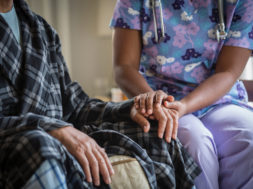 African American nurse holding patient’s hand