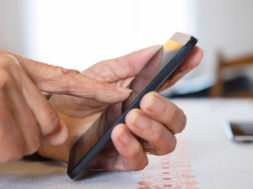 Female mature writing cell phone indoors closeup
