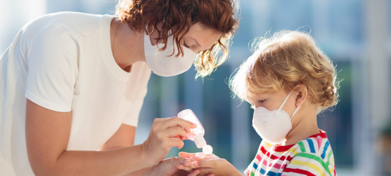 Mother and child with face mask and hand sanitizer