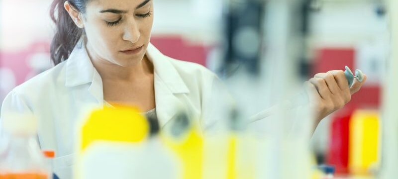 Concentrated chemist holding pipette at laboratory
