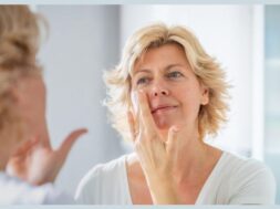Mid adult woman spreading a layer of facial cream in front of the mirror