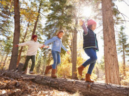 Children Having Fun And Balancing On Tree In Fall Woodland