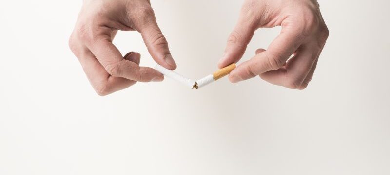 person-s-hand-breaking-cigarette-white-background