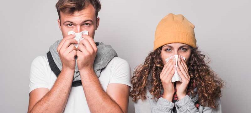 portrait-couple-blowing-their-nose-with-tissue-paper-gray-background