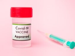 approved-covid-19-vaccine-bottle-disposable-syringe-injection-pink-background_177415-877