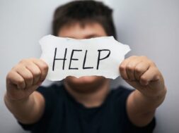 lonely-teenage-boy-depressed-expression-showing-paper-with-help-text_1212-1472