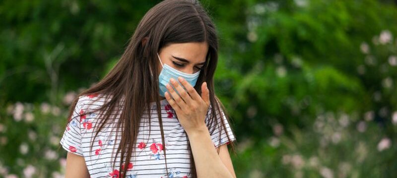 portrait-young-woman-wearing-protective-mask-sneezes-green-nature-background-with-flowers-protective-medical-mask_1212-2468
