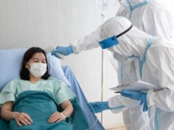 two-doctor-wear-ppe-suit-with-face-mask-measure-body-temperature-coronavirus-infected-patient-with-infrared-thermometer-gun-negative-pressure-quarantine-room_60388-708