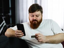 fat-man-types-number-credit-card-his-phone-sitting-couch_8353-5515