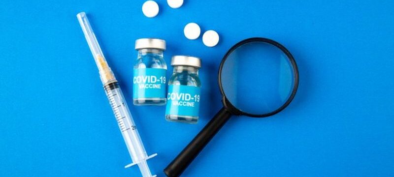 top-view-covid-vaccine-with-magnifier-injection-pills-blue-background-hospital-health-covid-lab-science-pandemic-virus-drug_179666-19746