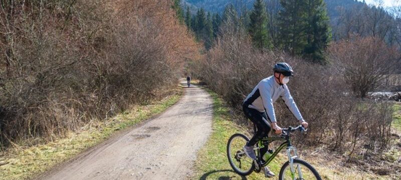 view-male-riding-bycicle-road-surrownded-by-trees-during-coronavirus-quarantine_181624-18421