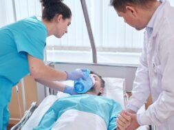 young-nurse-putting-bag-valve-oxygen-mask-patients-face-doctor-checking-his-pulse-while-they-providing-urgent-assistance-man_274679-10057