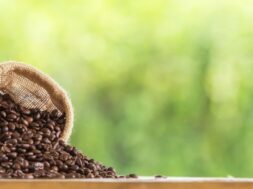 coffee-bean-sack-wooden-tabletop-against-grunge-green-blur-background_1323-255