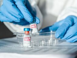 doctor-nurse-protective-suit-holding-covid-19-vaccine_266247-2041