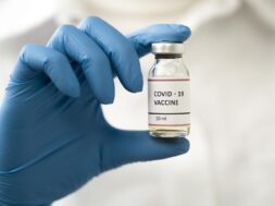 front-view-doctor-holding-coronavirus-vaccine_23-2148533490