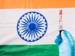hands-doctor-wearing-gloves-holding-blood-test-tube-coronavirus-covid-19-virus-laboratory-flag-india_143683-1216