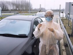 medical-heath-care-worker-protective-white-suit-standing-border-crossing-ready-test-passengers-corona-virus_308072-42