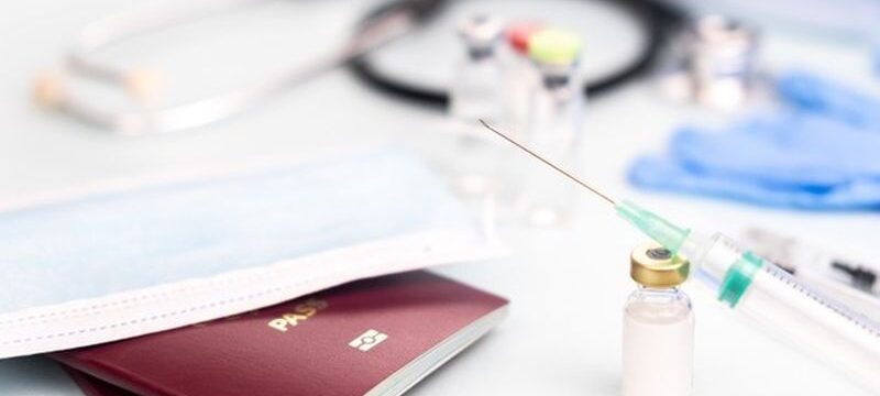 passports-with-medical-mask-with-ampoule-mock-up-vaccination-with-syringe-blurred_323347-265