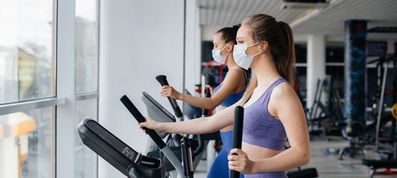 two-young-beautiful-girls-exercise-gym-wearing-masks-during-pandemic_180601-9453