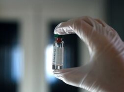 close-up-fingers-hand-medical-glove-hold-glass-bottle-medicine_254554-119