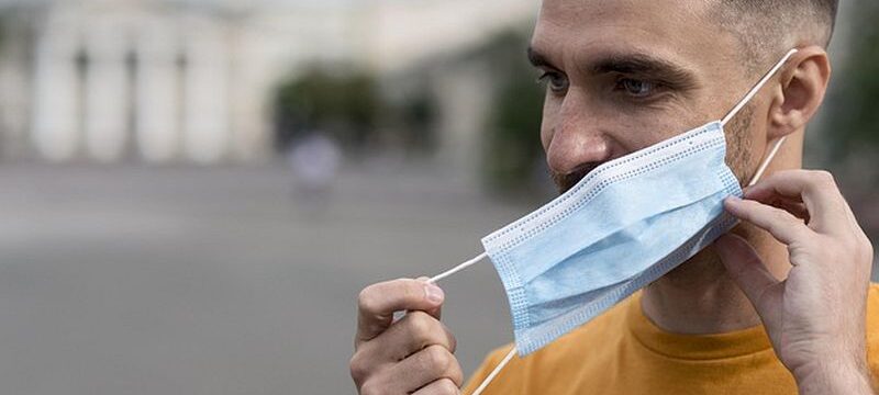 man-taking-off-his-medical-mask-outdoors_23-2148648198