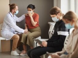 male-doctor-supporting-patient-while-she-crying-they-sitting-corridor-hospital-with-other-people_249974-5230