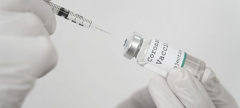 medic-with-latex-gloves-holding-vaccine-vial-syringe_23-2148988293