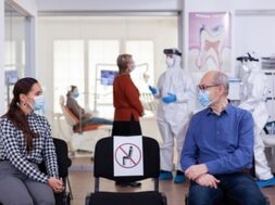 senior-man-with-face-mask-discussing-with-woman-patient-stomatology-clinic-waiting-room-keeping-social-distancing-during-global-pandemic-with-coronavirus_482257-4817