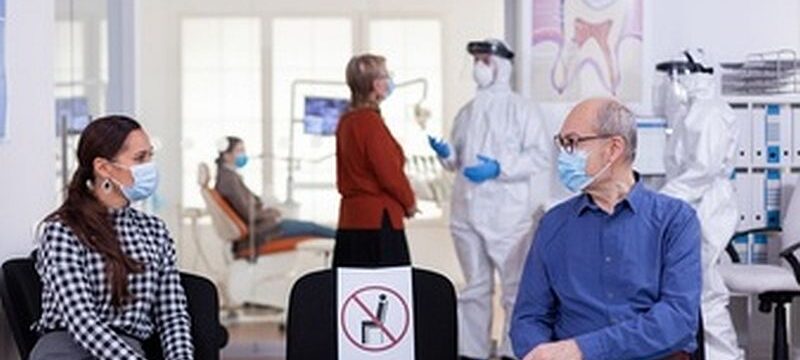 senior-man-with-face-mask-discussing-with-woman-patient-stomatology-clinic-waiting-room-keeping-social-distancing-during-global-pandemic-with-coronavirus_482257-4817