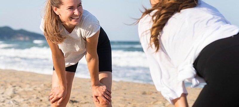 two-women-exercising-together-beach_23-2148694872