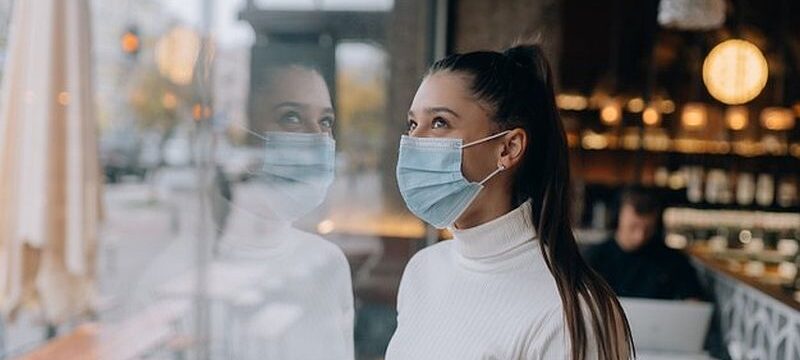 young-woman-face-mask-standing-front-windows-cafe_1153-8035