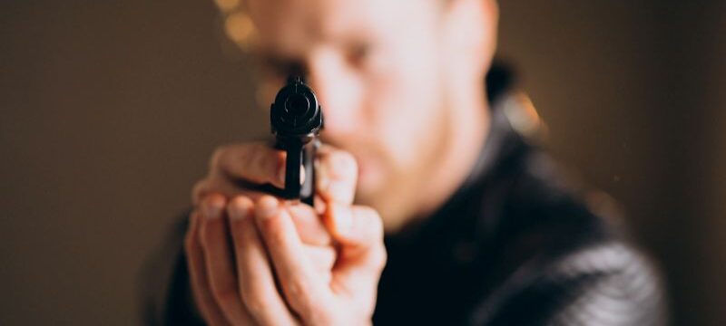 Handsome man actor posing in studio with weapon