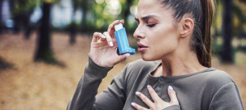 Young woman treating asthma with inhaler