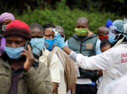 A health worker takes the temperature of a person standing in line for mass testing in an effort to stop the spread of the coronavirus disease (COVID-19) in the Kibera slum of Nairobi