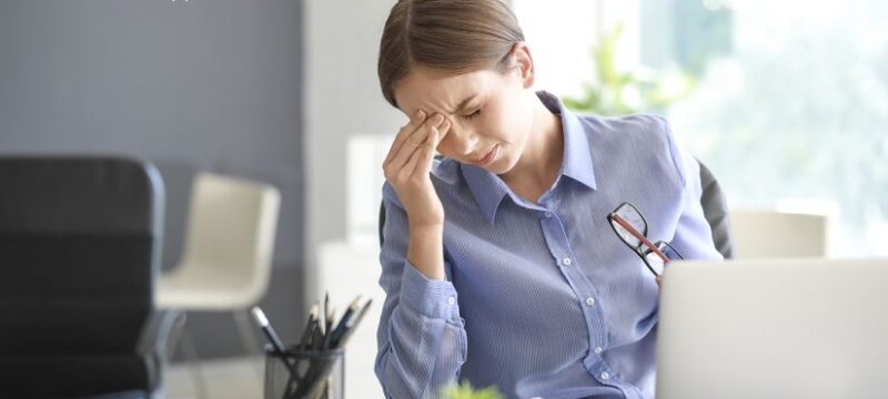 Young woman suffering from headache in office