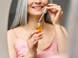 Closeup cut shot of mature Asian woman holding pipette and bottle serum.