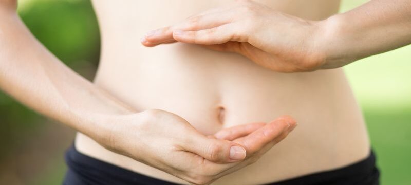 Close-up of young womans hands and slim belly