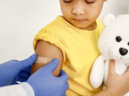 Doctor stick a band-aid on a girl’s shoulder after a vaccination