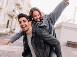 Excited man in black denim jacket chilling with girlfriend. Outdoor photo of happy couple exploring city.