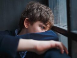 teenaged-boy-curled-up-wide-eyes-staring-out-window-768