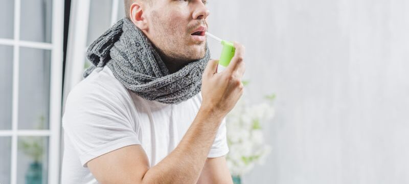 young-man-suffering-from-cold-treats-her-throat-with-spray