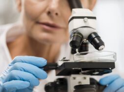 defocused-female-scientist-looking-through-microscope