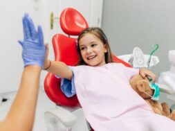 Cute little girl sitting on dental chair and having dental treatment.